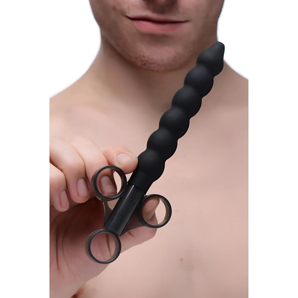 A person holding a black, silicone CleanStream beaded lubricant launcher with a syringe-style three-ring finger grip.