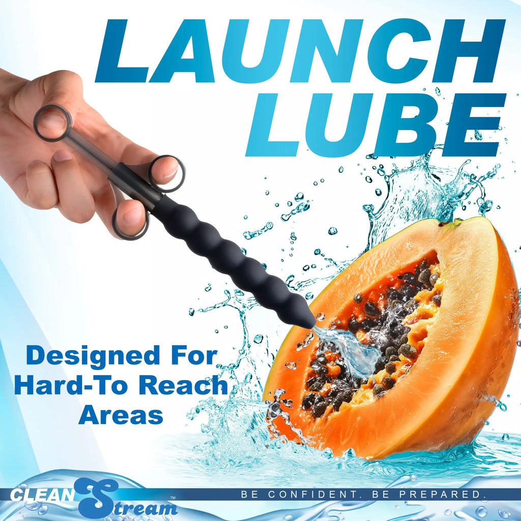 CleanStream Silicone Beaded Lubricant Launcher: A black, beaded syringe tool sprays water into a halved papaya.