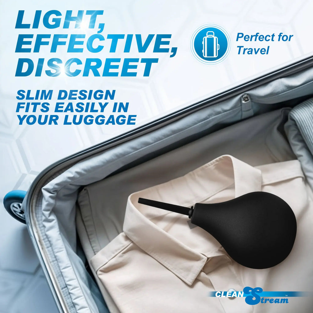 CleanStream Thin Tip Enema Bulb: a black, slim-tip bulb rests inside an open suitcase on top of folded clothing.