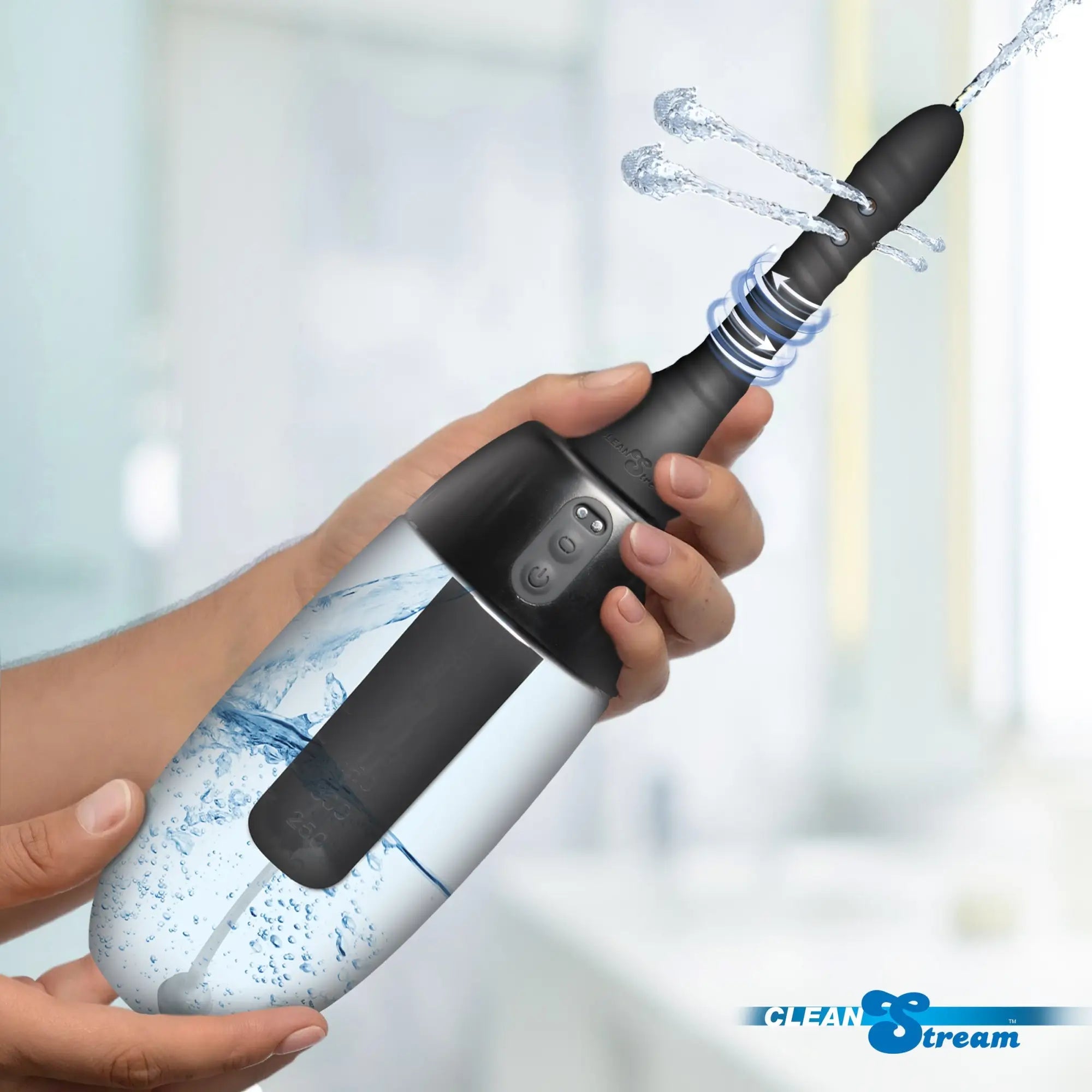 CleanStream XL black automatic enema bulb with spinning tip, spraying water, held in hand against a blurred background.