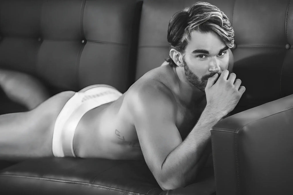 A man lying on a couch wearing white clever 1034 lucerna thongs made of soft breathable fabric shown from the back