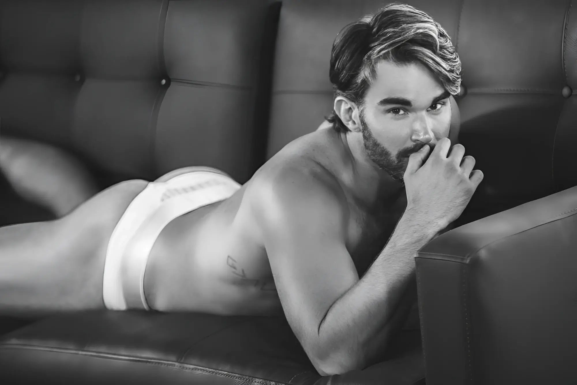 A man lying on a couch wearing white clever 1034 lucerna thongs made of soft breathable fabric shown from the back