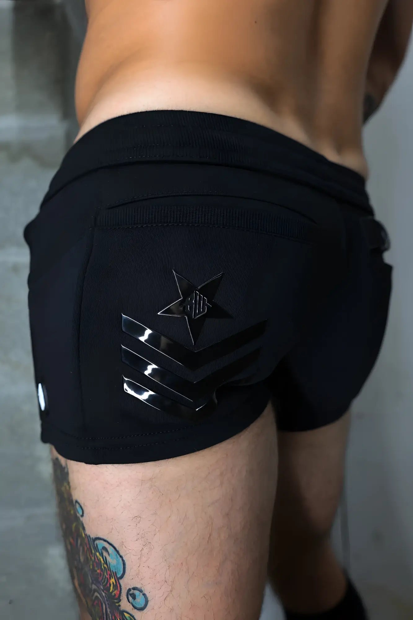 Black cockpit shorts back side showing glossy black star and three horizontal stripes on athletic fabric