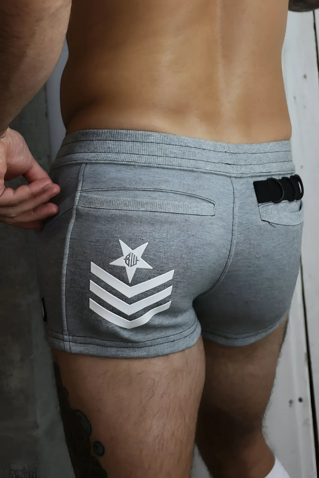 Back view of gray heathered cockpit shorts with white star and chevron insignia for athletic use