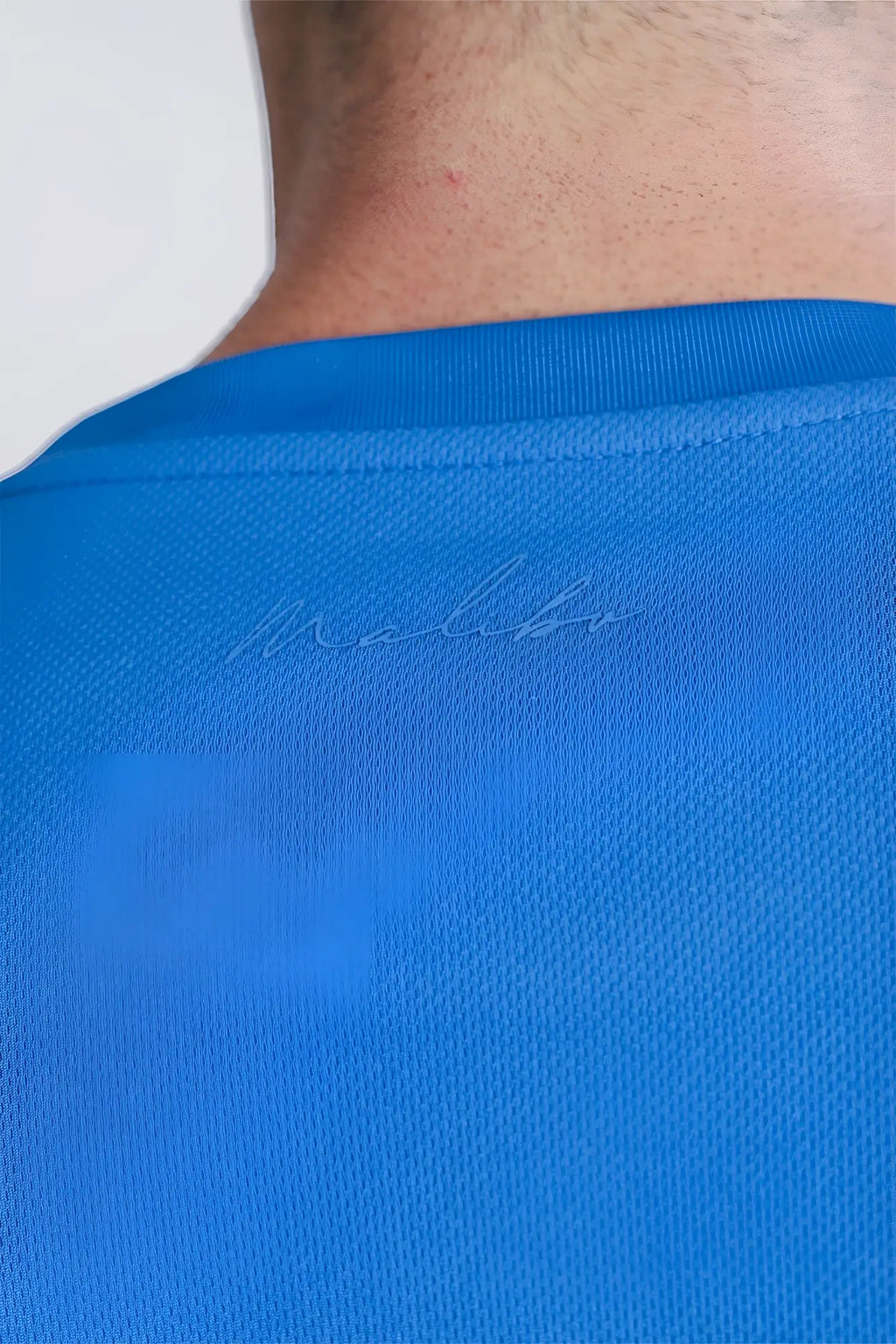 Back view of bright blue cool-dry oversized relaxed crop top made of textured fabric with subtle embroidered malibu logo