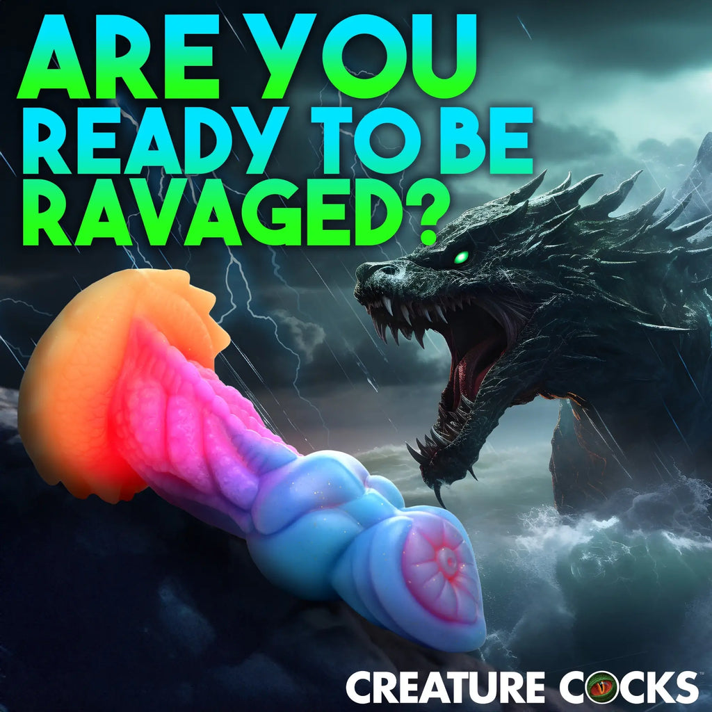 Creature Cocks Aqua-Cock glow-in-the-dark silicone dildo with textured blue, pink, and orange dragon-like features.