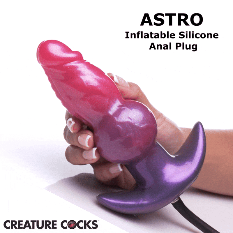 A hand holds a pink and purple Creature Cocks Astro inflatable silicone anal plug with a flared base and tube.