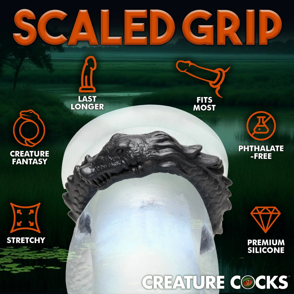 Creature Cocks Black Caiman silicone cock ring, featuring a textured, scaly alligator head design against a swamp background.