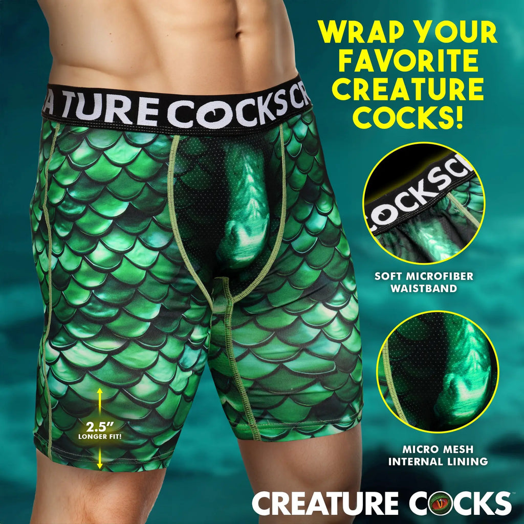Creature Cocks Cockness Monster boxer shorts in green dragon-scale print, featuring a black waistband and mesh details.