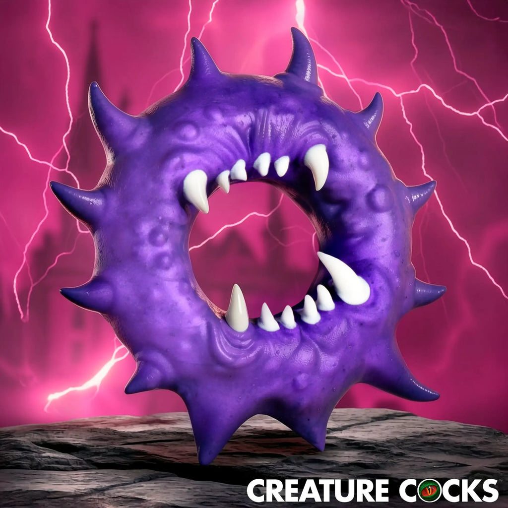 Creature Cocks Constrictor: A purple, spiked silicone cock ring with white fangs against a pink lightning background.