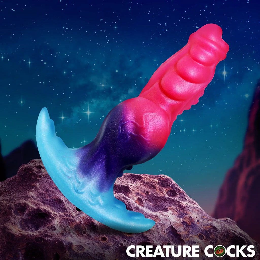 Creature Cocks Cosmo Hound silicone butt plug in a glittery blue, purple, and pink gradient, set against a space backdrop.
