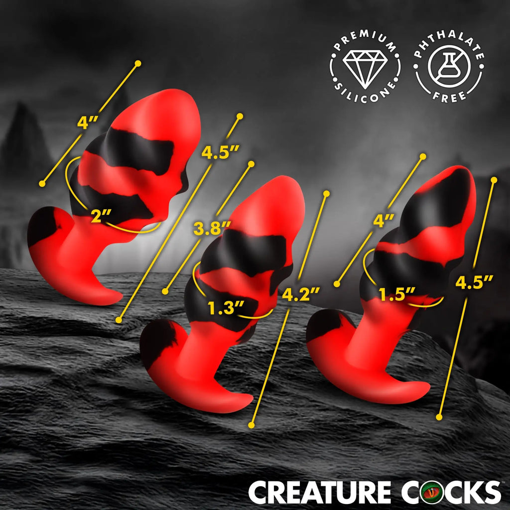 Creature Cocks Dragon Trainer silicone butt plug set in red and black, shown with size measurements on a dark surface.