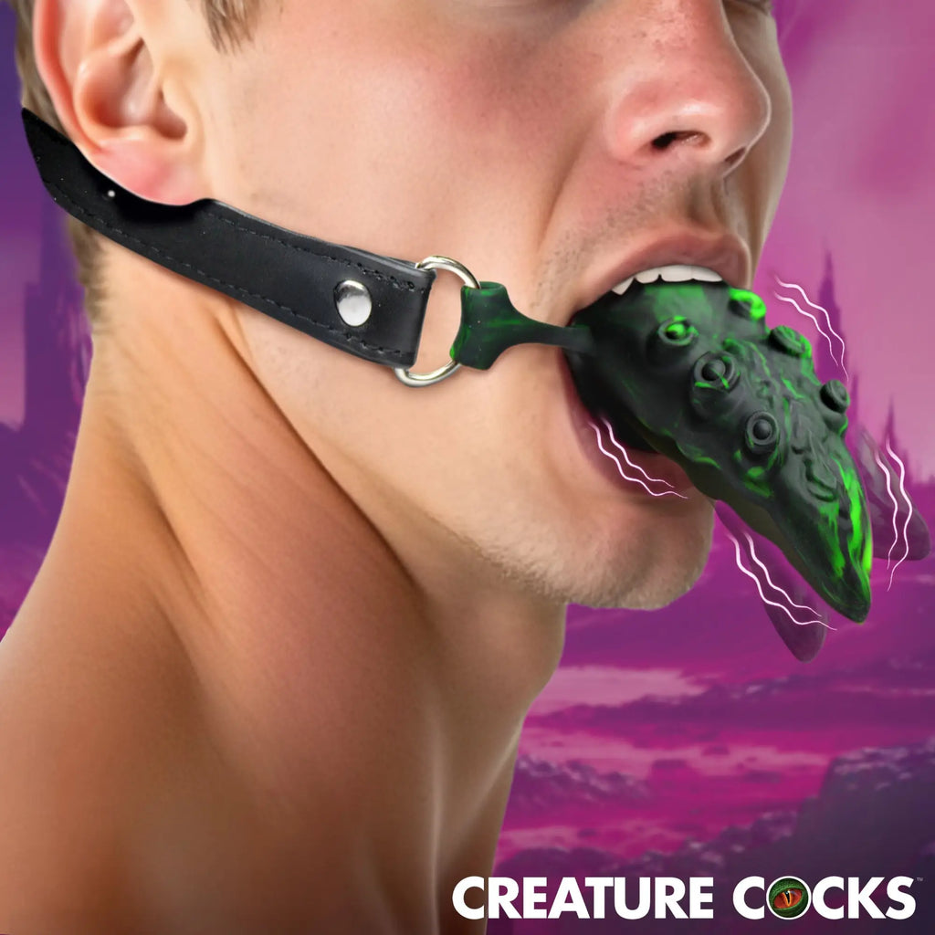 Creature Cocks Dragon's Lick: a green-and-black textured vibrating oral enhancer on a black leather head harness.