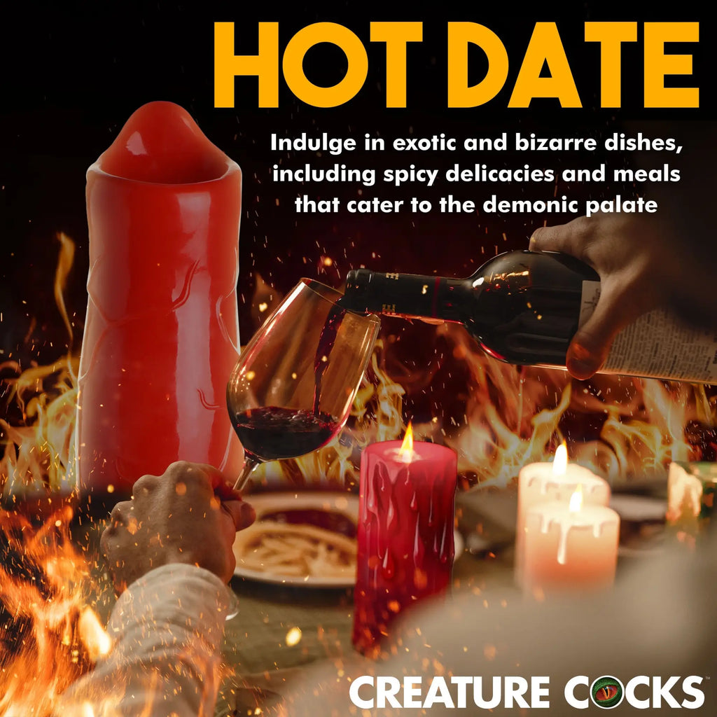 Red Creature Cocks Giant Hell-Hound dildo displayed on a table with wine, candles, and a fiery background.