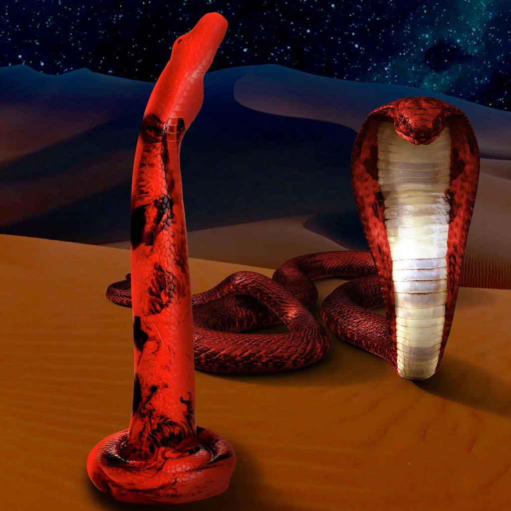 Creature Cocks Giant King Cobra silicone dildo in red with black markings, shown against a desert and starry night sky.