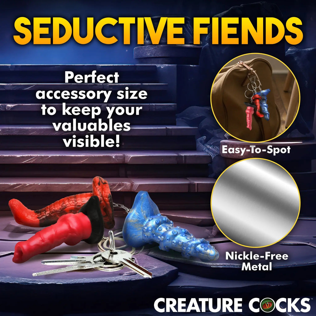 Creature Cocks keychain set featuring red, black, and blue textured silicone charms hanging on metal key rings.