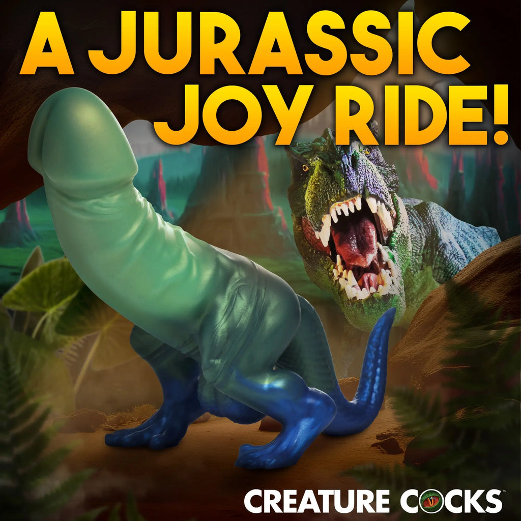 Creature Cocks Jurassic Cock silicone dildo in blue and green, set against a T-Rex jungle background.