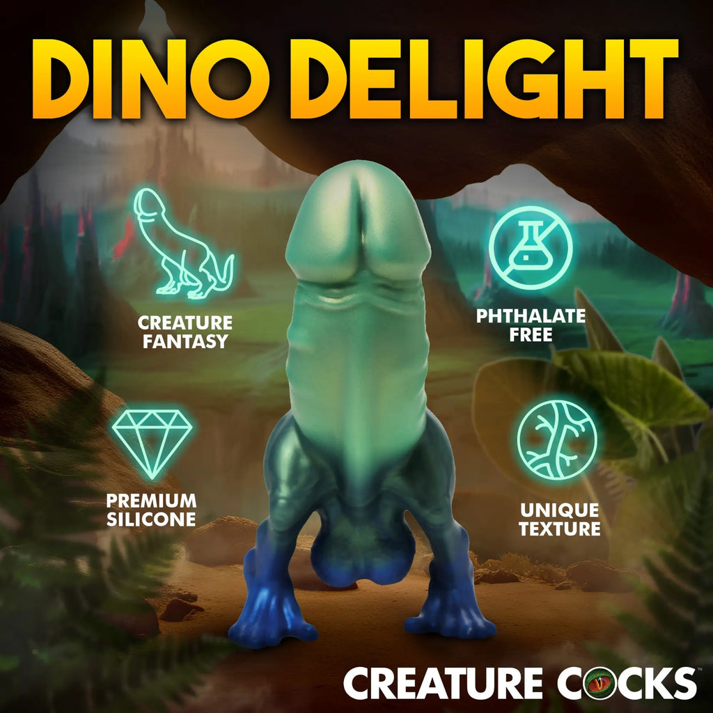 Creature Cocks Jurassic Cock silicone dildo: a green-to-blue gradient dinosaur-themed toy in a prehistoric setting.