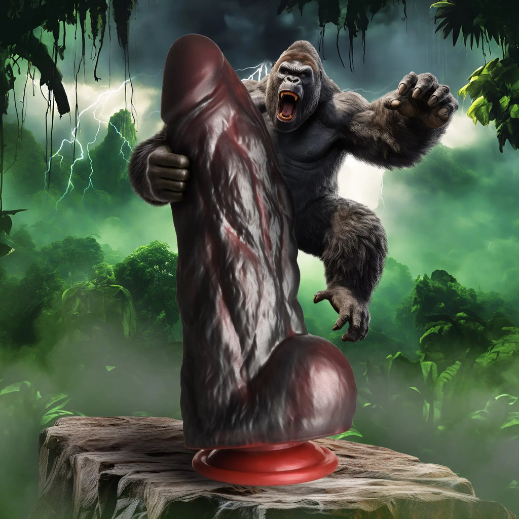 Creature Cocks King Kong dark brown silicone dildo with textured surface and red base on a rock in a jungle.