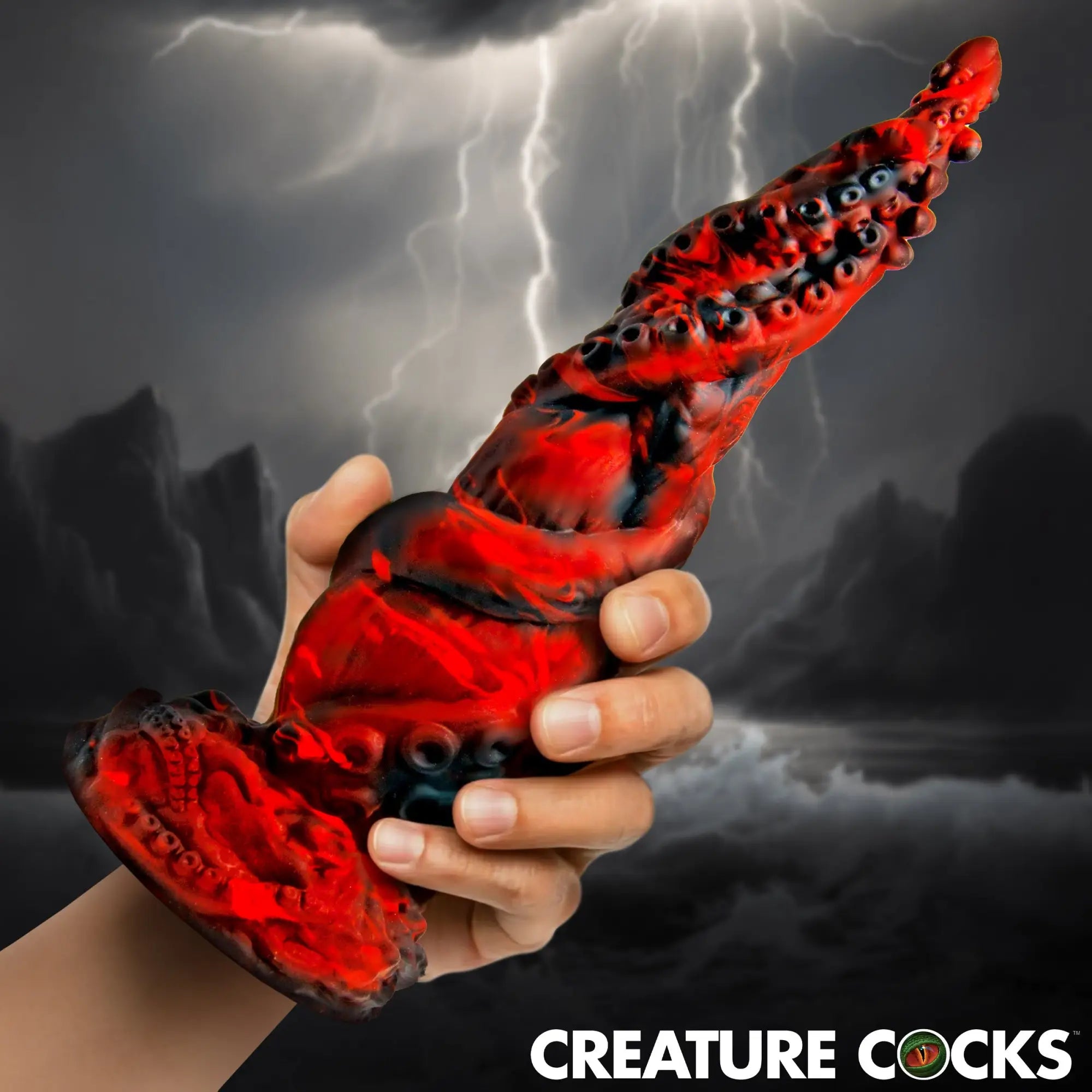 A hand holds a red and black marbled Creature Cocks Kraken Spawn tentacle dildo against a stormy, lightning-filled sky.