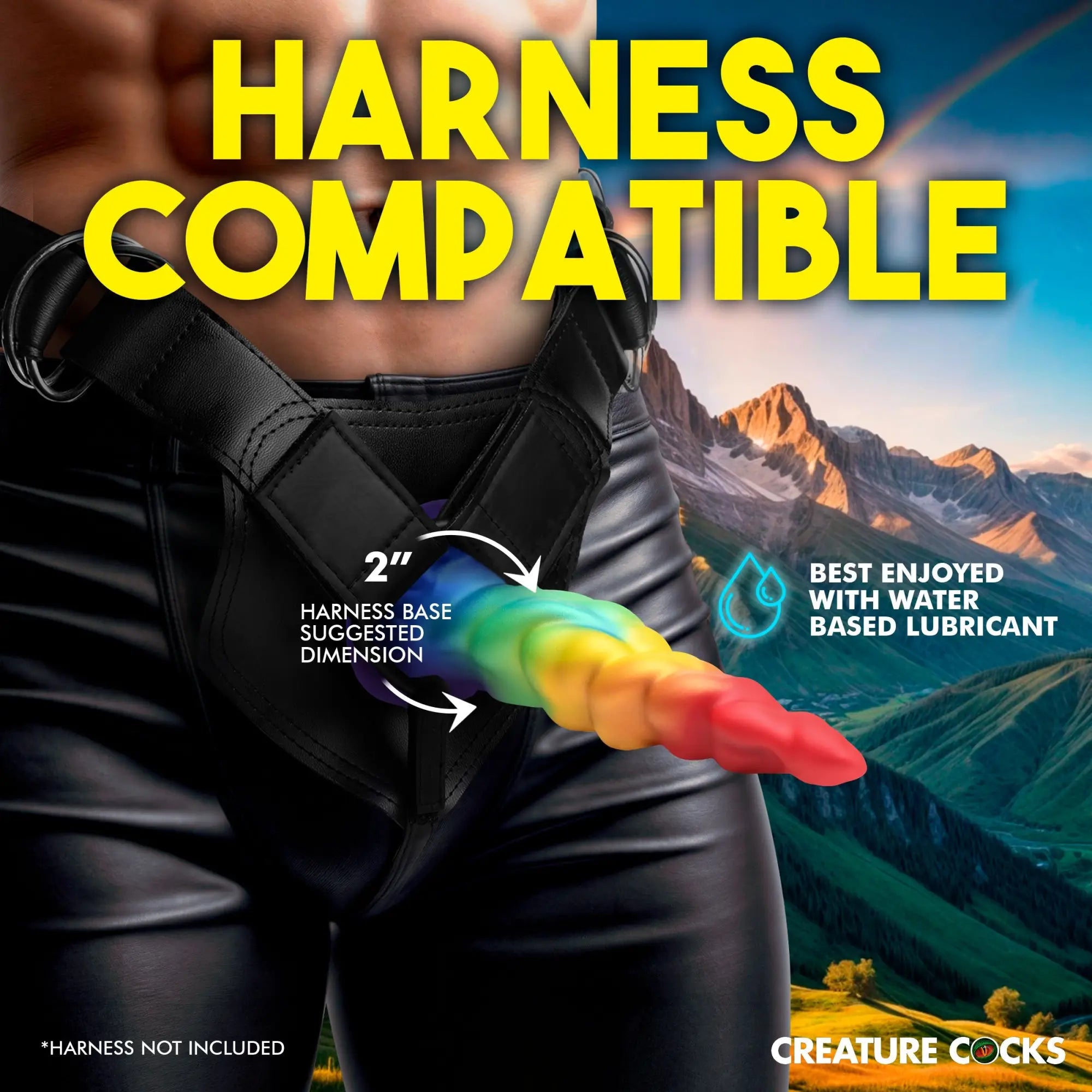 Creature Cocks Magic Rider rainbow silicone unicorn dildo in a black leather harness against a mountain background.