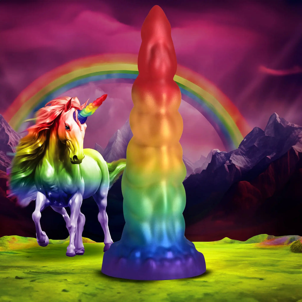 Creature Cocks Magic Rider rainbow silicone dildo in front of a majestic unicorn and mountain landscape with a rainbow.