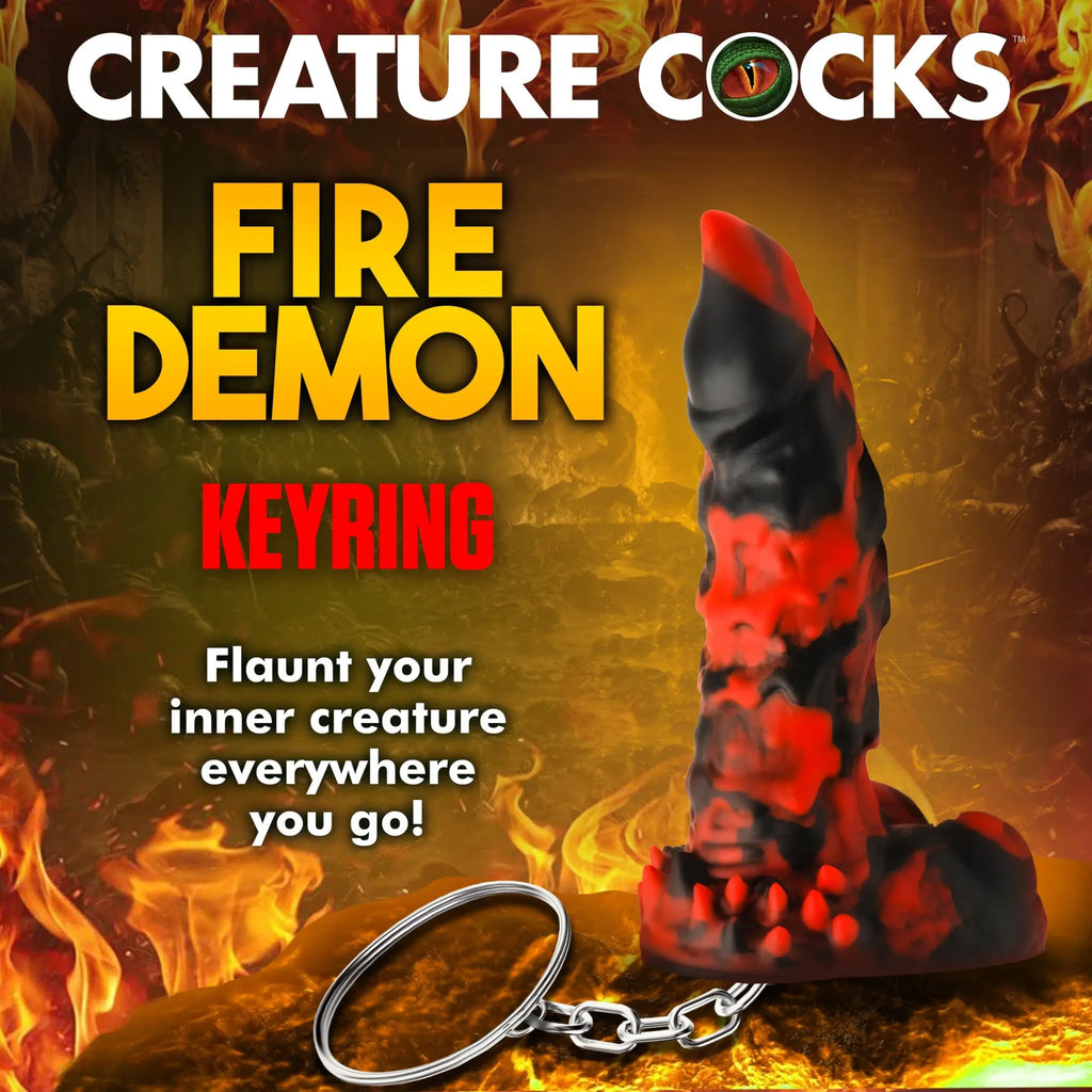 Creature Cocks Fire Demon mini dildo keychain in black and red textured design against a fiery background.