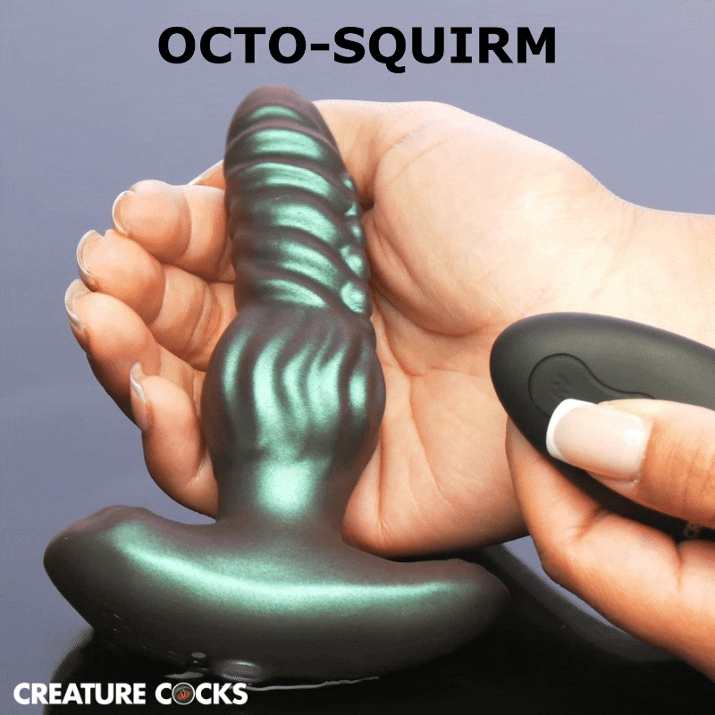 Creature Cocks Octo-Squirm metallic green silicone anal plug with ribbed texture held in a hand next to a remote.