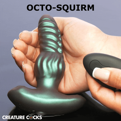 Creature Cocks Octo-Squirm metallic green silicone anal plug with ribbed texture held in a hand next to a remote.