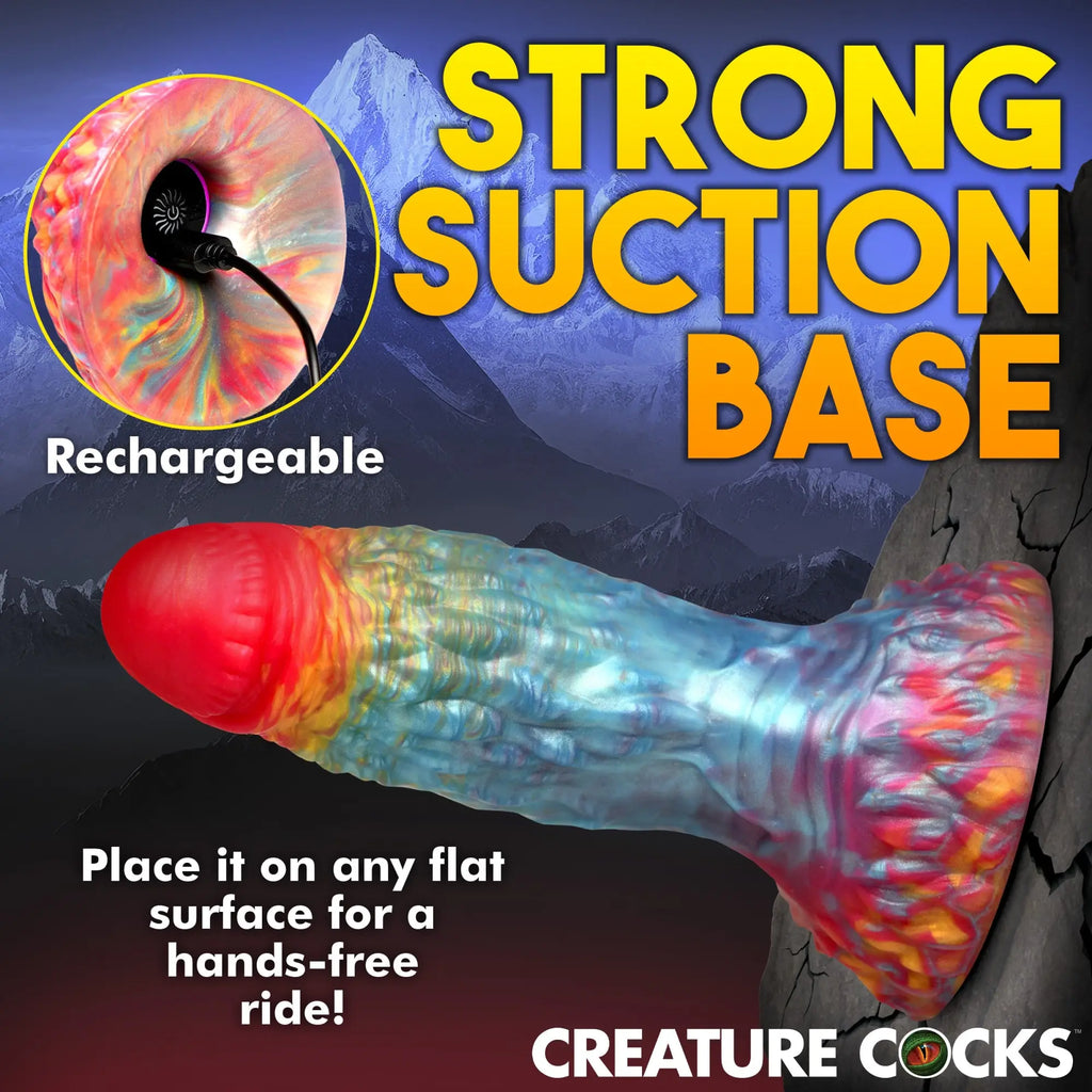Creature Cocks Rainbow Phoenix dildo with textured surface, red tip, multicolored body, and suction base on a rock face.