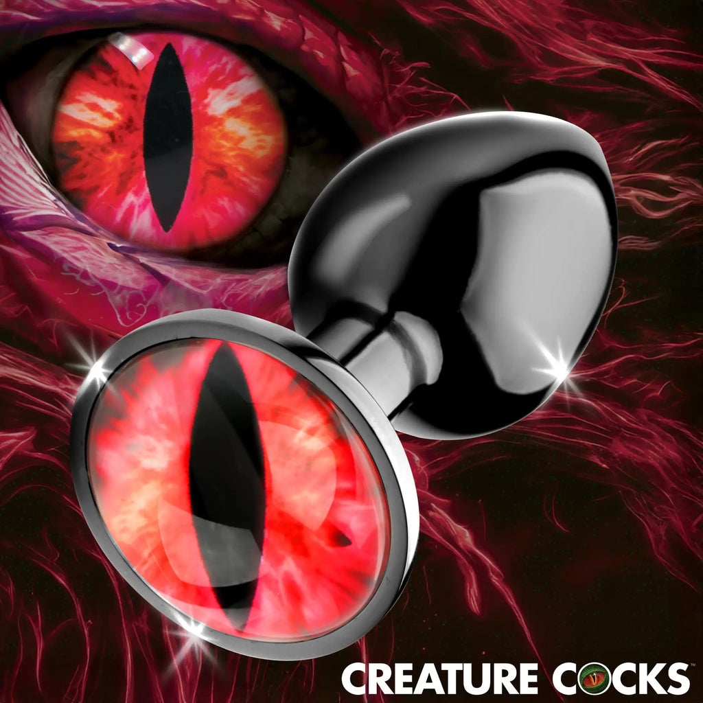 Creature Cocks Sinister Eye metal butt plug featuring a polished black teardrop base and a red reptilian eye design.