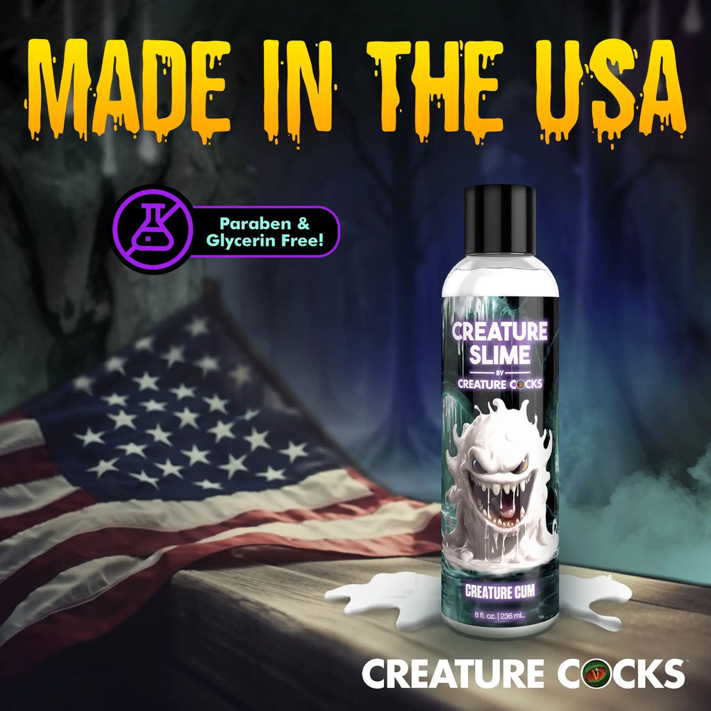 Creature Slime lubricant bottle with white monster graphic on a wooden surface with a US flag background.
