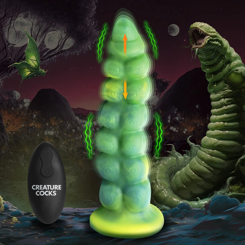 Creature Cocks Squirmer silicone dildo: neon green, segmented design with a remote control, set in a surreal landscape.