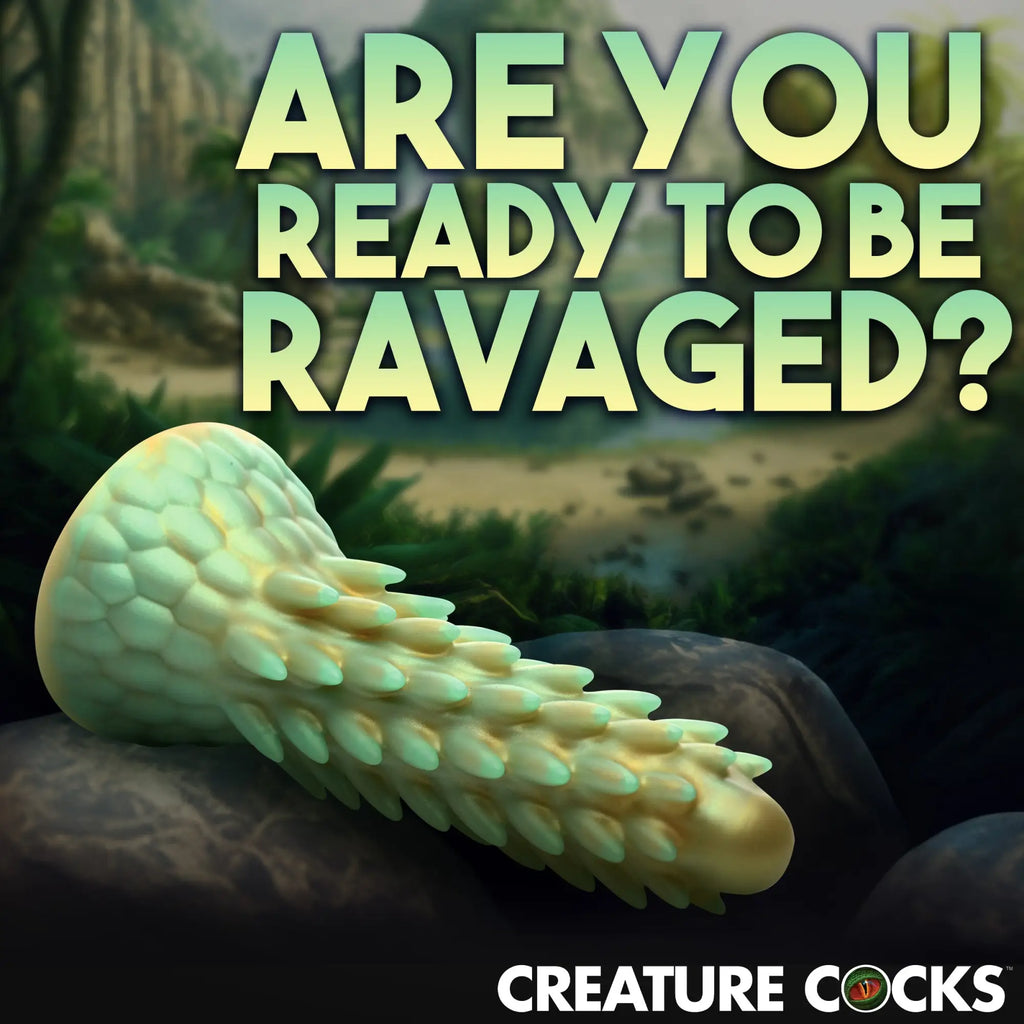 Creature Cocks Stegosaurus silicone dildo: a spiky, pale green reptile-themed toy resting on a rock in a jungle setting.