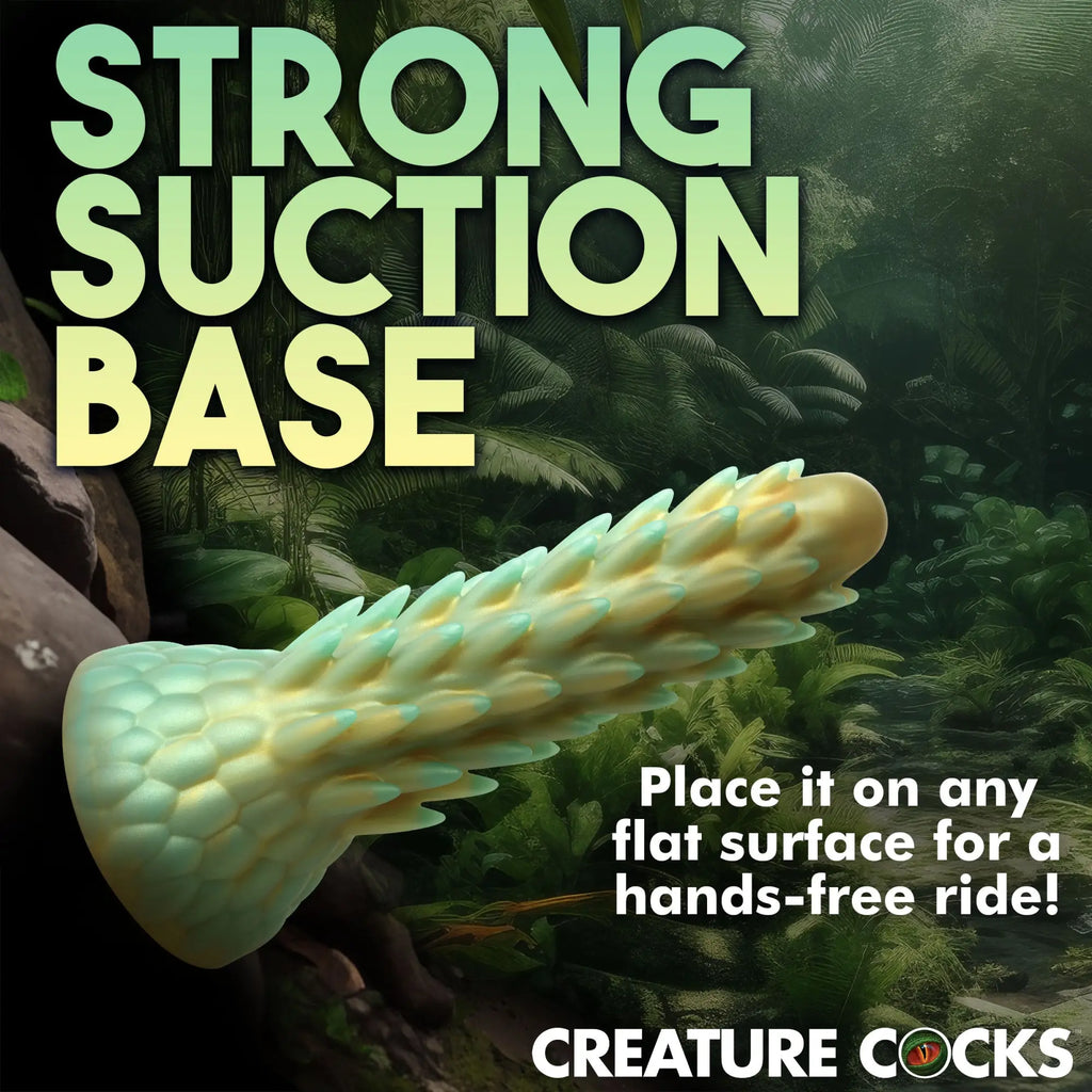 Creature Cocks Stegosaurus dildo in a green and yellow textured, spiky design against a lush jungle background.
