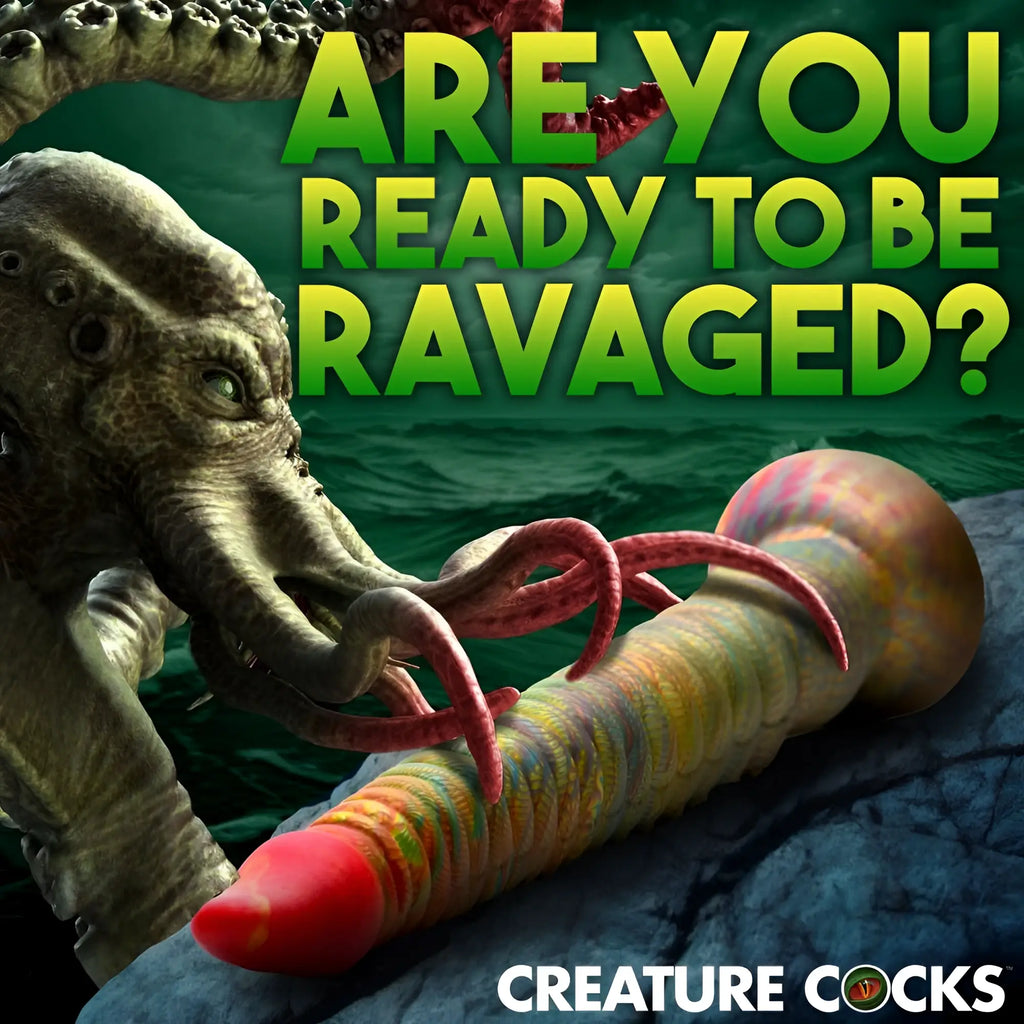 Creature Cocks Tenta-Dick: A colorful, ribbed silicone tentacle dildo with a red tip on a rocky shore by a sea monster.