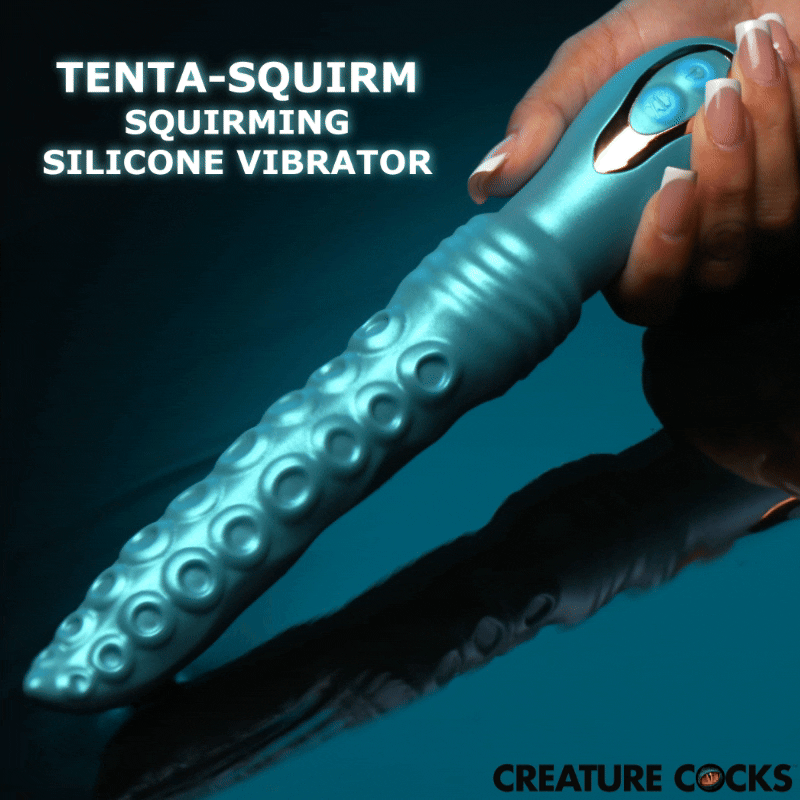 A hand holds a metallic blue, tentacle-shaped Creature Cocks Tenta-Squirm silicone vibrator against a dark background.