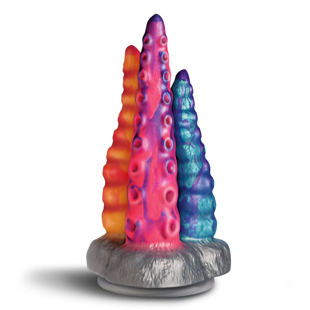 Creature Cocks Tenta-Trio silicone dildo features three multicolored, tentacle-shaped shafts on a textured grey base.