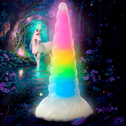 Creature Cocks Uni-Glow dildo: a spiral, rainbow-colored, glow-in-the-dark silicone toy against a unicorn forest backdrop.