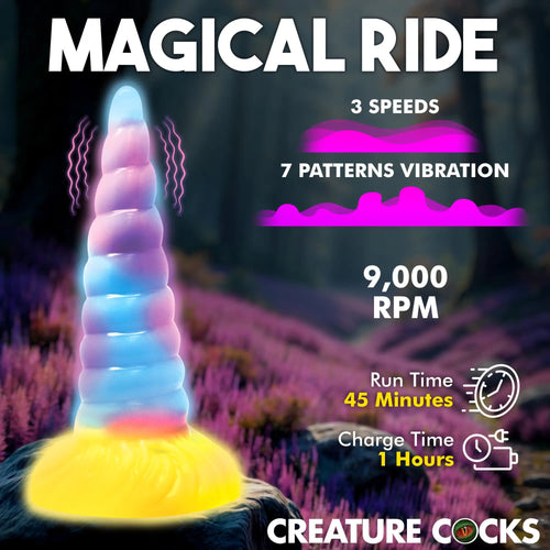 Creature Cocks Unicorn vibrating silicone dildo with blue-to-pink gradient horn and glowing yellow base on a rock.