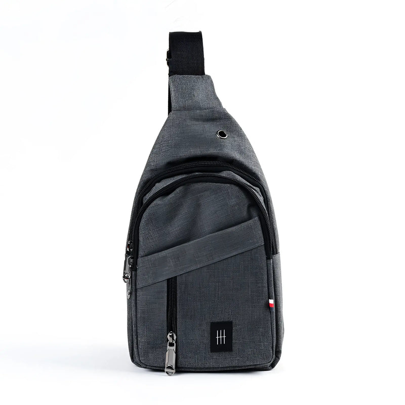 Crossbody sling bag made of gray textured fabric with black zipper pulls and a small black logo patch