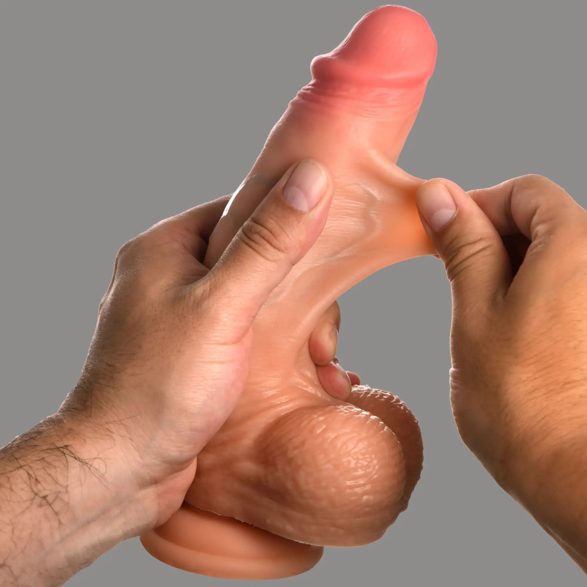 Curve Toys 8-inch realistic silicone dildo with balls, showing flexible, stretchable skin-like material being pulled.