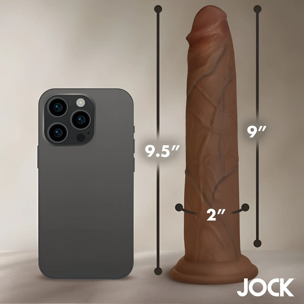 Curve Toys 9.5-inch brown silicone dildo shown next to a smartphone for size comparison with measurements.
