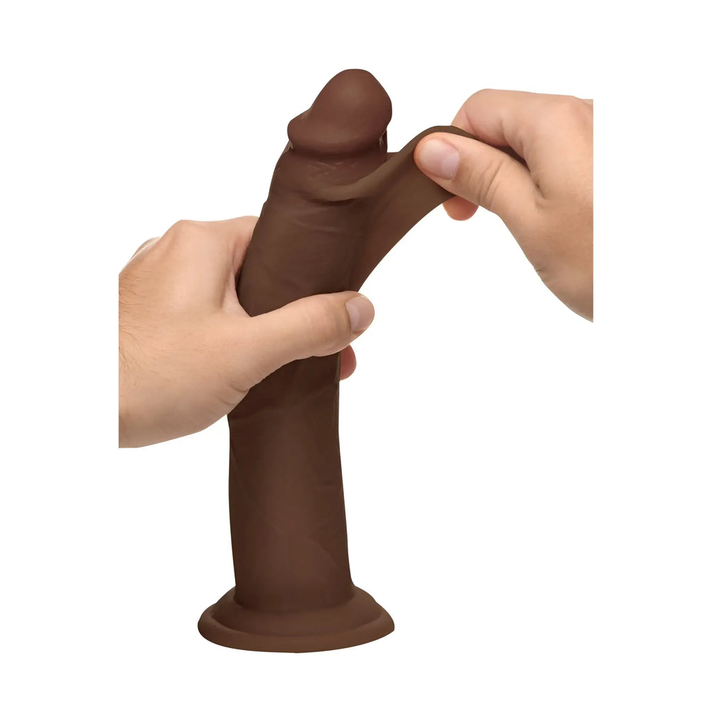 Hands stretching the flexible, dark brown Curve Toys 9.5-inch Real Skin silicone dildo against a white background.