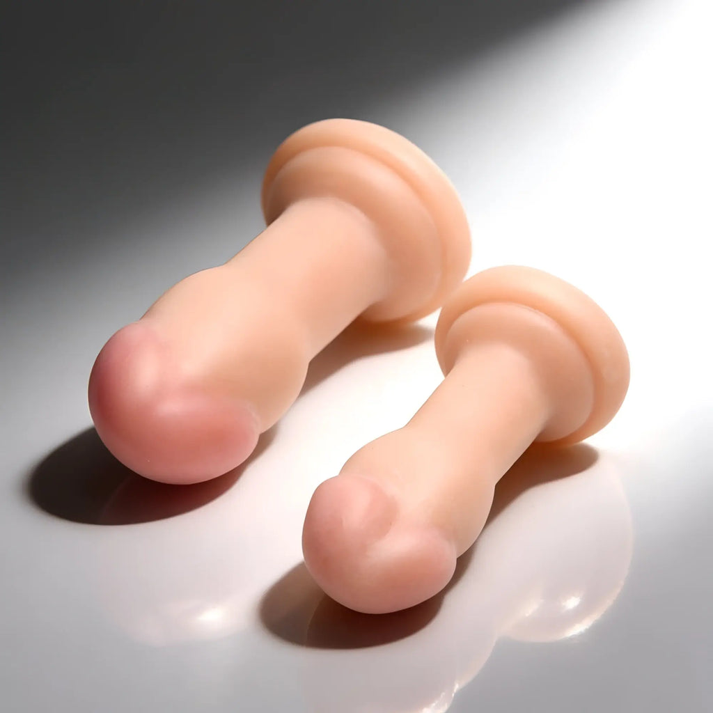 Curve Toys Duo Jock anal plugs: two smooth, peach-colored, phallic-shaped silicone plugs on a white reflective surface.