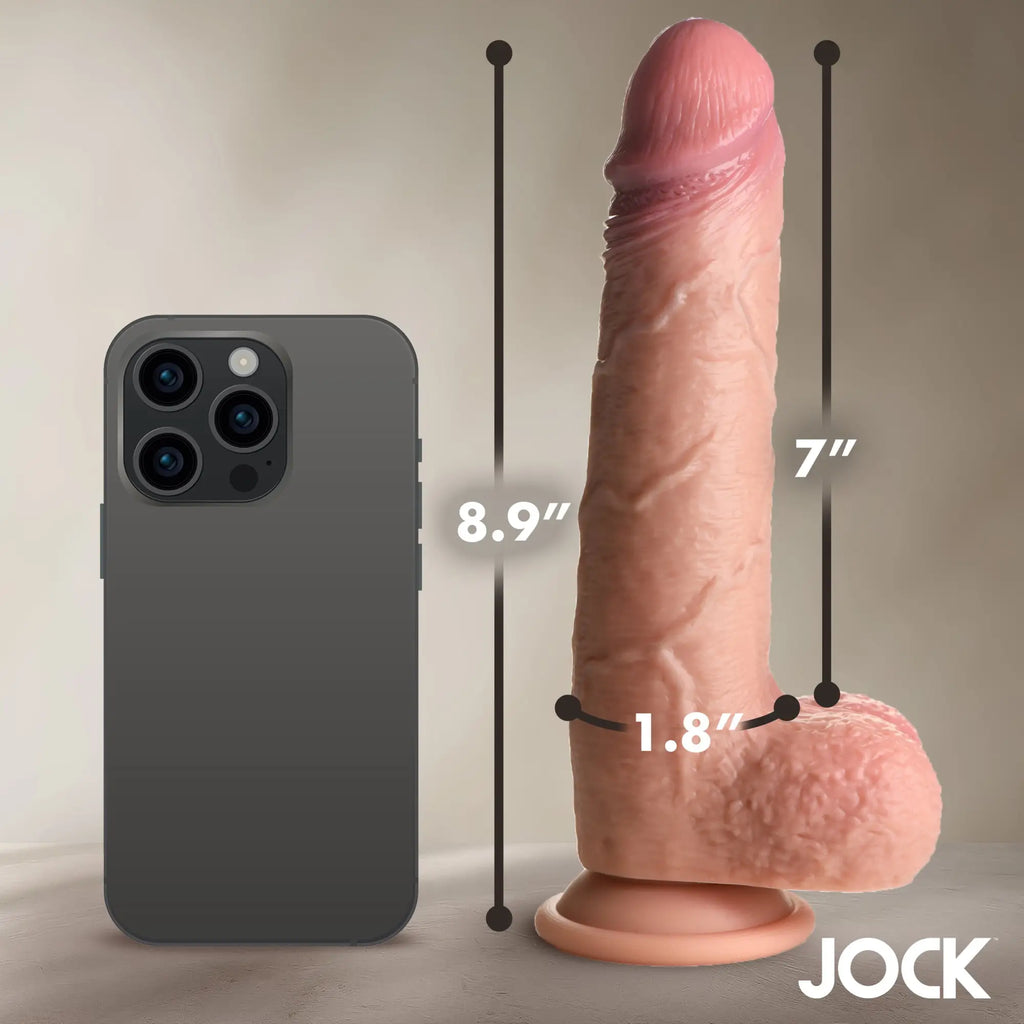 Curve Toys JOCK silicone dildo in flesh tone next to a smartphone for size reference with measurement labels.