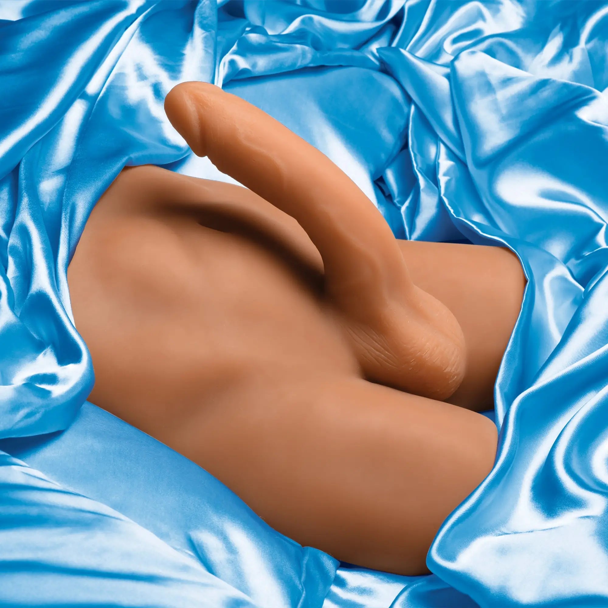 Curve Toys male ass masturbator with a posable dildo, featuring realistic tan silicone skin on blue satin fabric.