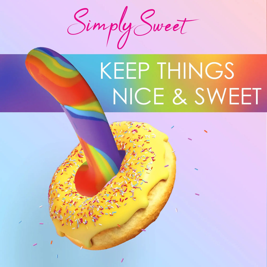 Curve Toys rainbow silicone dildo protruding from a yellow-frosted donut with sprinkles against a colorful background.