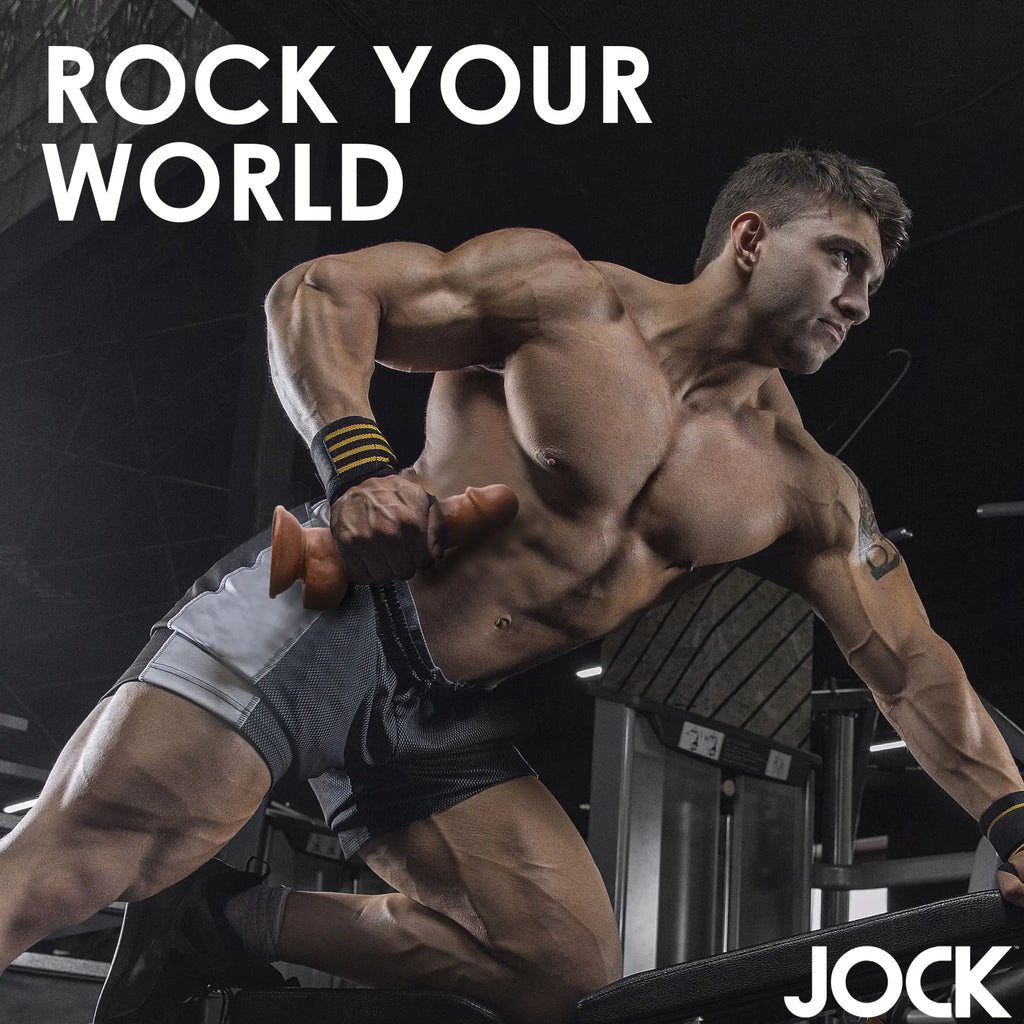 A muscular man at the gym holds a brown, dumbbell-shaped Curve Toys Weightlifting Wesley 7-inch dildo.