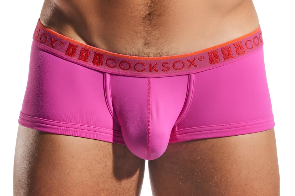 Bright pink form-fitting men’s briefs cx68n trunk with an orange waistband featuring the anuccocksox logo in red lettering